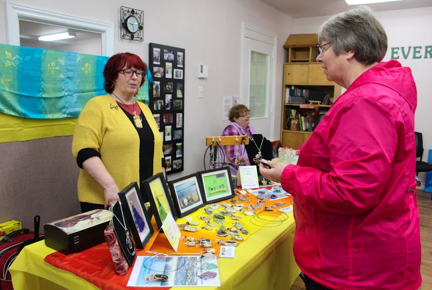 Some jewelry caught the attention of Mona Walker, right, at the Vendor Village on Thursday at the Every Woman’s Centre on Trinity Avenue, Sydney. Wanda Earhart, left, provided some information on the jewelry, which joined leather craft, clothing, artwork and other creations at the village.