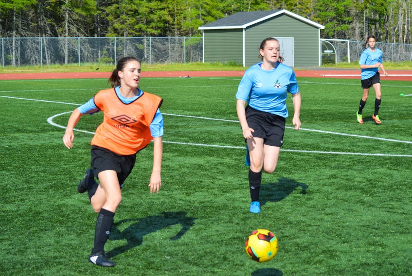 In this file photo, Lila MacLeod, left, heads up the field while being chased by Chloe Parsons during a Cape Breton FC girls’ soccer team practice at the Cape Breton Health Recreation Complex turf field last June. A pair of local Cape Breton FC clubs will return to the pitch this weekend to open their 2018 Nova Scotia Soccer League seasons.