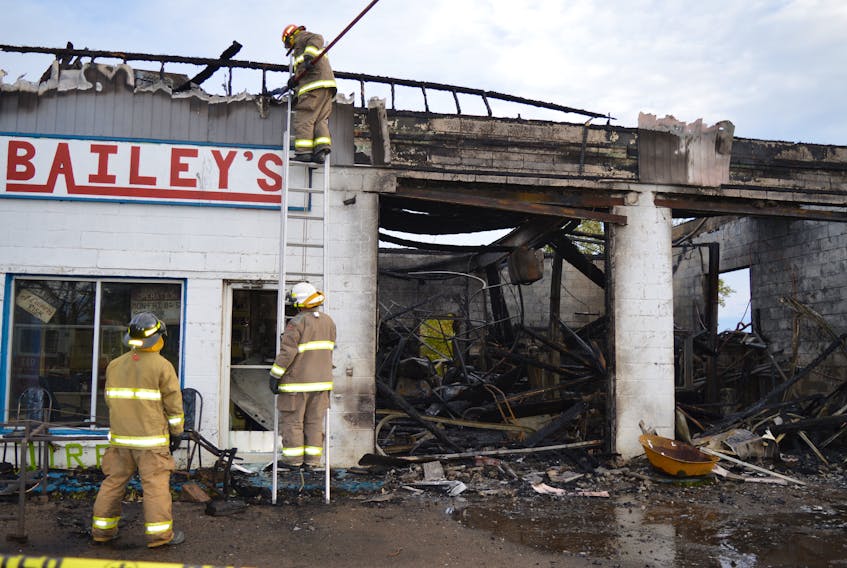 Members of the Dominion Volunteer Fire Department, from left, firefighter Edward MacNeil, Fire Chief Scott Duffney and fire captain Dave MacLeod, check out hot spots following a fire which destroyed Bailey’s Service Centre on King’s Road in Dominion, early Wednesday morning. Sharon Montgomery-Dupe/Cape Breton Post