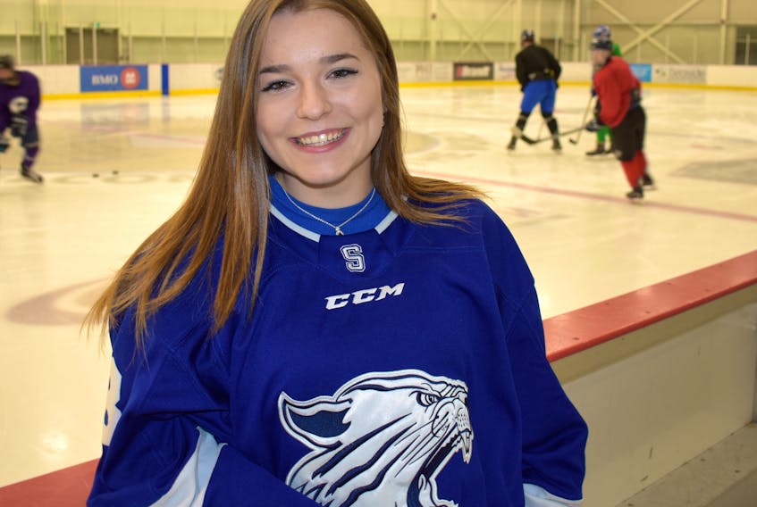 Belle Jacobs of the Sydney Academy Wildcats stands next to the players bench at the Membertou Sport and Wellness Centre. The 17-year-old is the first female hockey player to play for the Wildcats Division 1 hockey team.