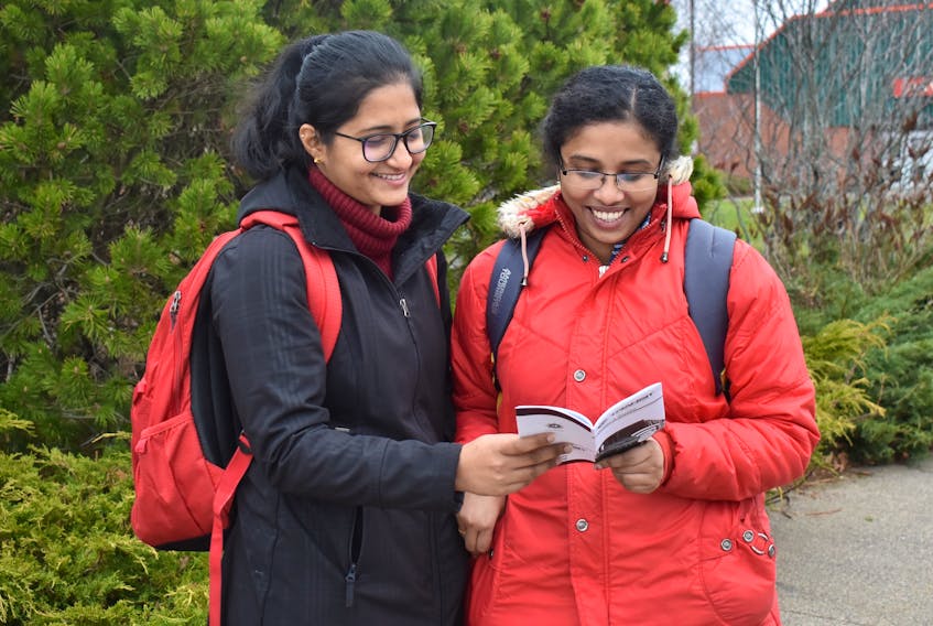 Public health students Steffi Sebastian and Siju Abraham consult the new Transit Cape Breton bus schedule while waiting for a ride at the Cape Breton University on Monday. The Glace Bay residents have been attending CBU since January and say the local transit system has been reliable and efficient.