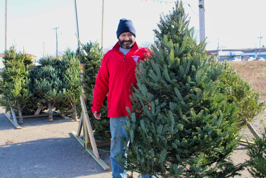 Billy Burke, a volunteer with the Glace Bay Y's Men's and Women's Club, stands by Christmas trees the group is selling to raise money for its annual adopt-a-family campaign. Tree sales have been down this year and organizers fear it will affect the number of families and organizations they can help during the holidays.