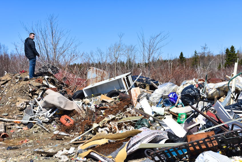 In this file photo, Dylan Yates, founder of the Cape Breton Environmental Association, looks over mounds of garbage that have been illegally dumped behind the water tower in Reserve Mines. Along with furnace pieces are vehicle parts, oil tanks, refrigerators and stoves.