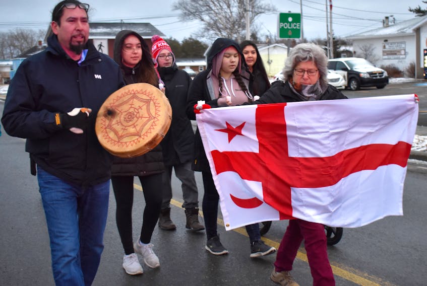 Jeff Ward sings and drums as he leads the candlelight vigil march in honour of Colton Boushie on Sunday in Membertou. Beside him, Laurie Doucette holds the Mi'kmaq flag as a small group of supporters follows behind.