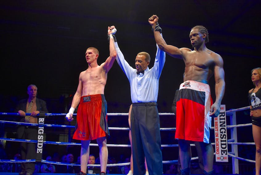 Referee Craig Smith, middle, lifts the arms of Aaron Crawley, right, of Dartmouth and Darren Fletcher of Brampton, Ont., following a six-round fight in the light heavyweight division during the Thunder on the Cape event at Centre 200 on May 19. A fight card was scheduled for next month in Sydney but has since been postponed until the new year.
