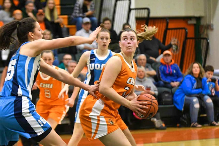 Hannah Brown, right, of the Cape Breton Capers works her way around Inga Aleksaite of the UQAM Citadins during Debbie Ruiz Memorial Basketball Tournament action at Sullivan Field House in Sydney on Friday.
