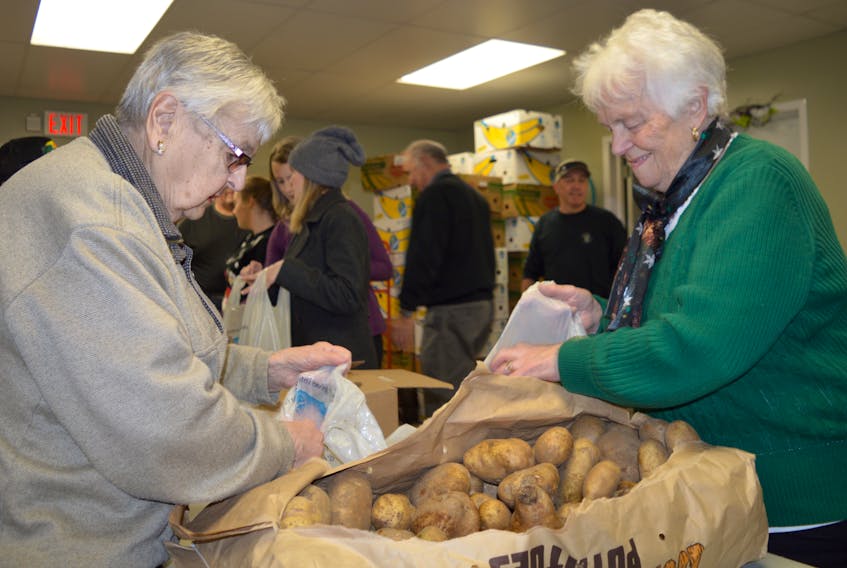 Ruby Pye, right, and Pencie Granchelli place potatoes in a bag in preparation for distribution as part of the annual Combined Christmas Cheer program at the Sydney Mines Food Bank, Tuesday. This year’s program will serve about 250 families and includes a Christmas dinner grocery order as well as knitted mittens, hats, scarves and more.