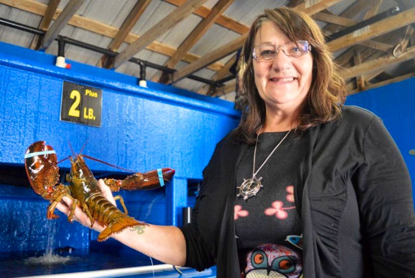 Marlene Brogran, manager at the Ballast Ground Fisheries, shows a still-frisky local lobster destined for someone’s plate.