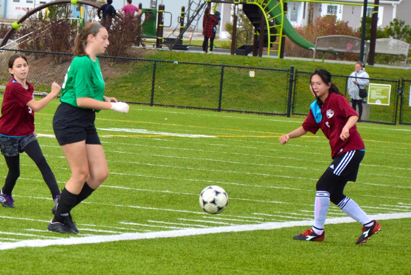 Amy Darling of Breton Education Centre, left, and Angelica Hu of Sherwood Park Education Centre look at the ball during Cape Breton Middle School Soccer League action at Open Hearth Park in Sydney on Tuesday. BEC won the game 2-0.