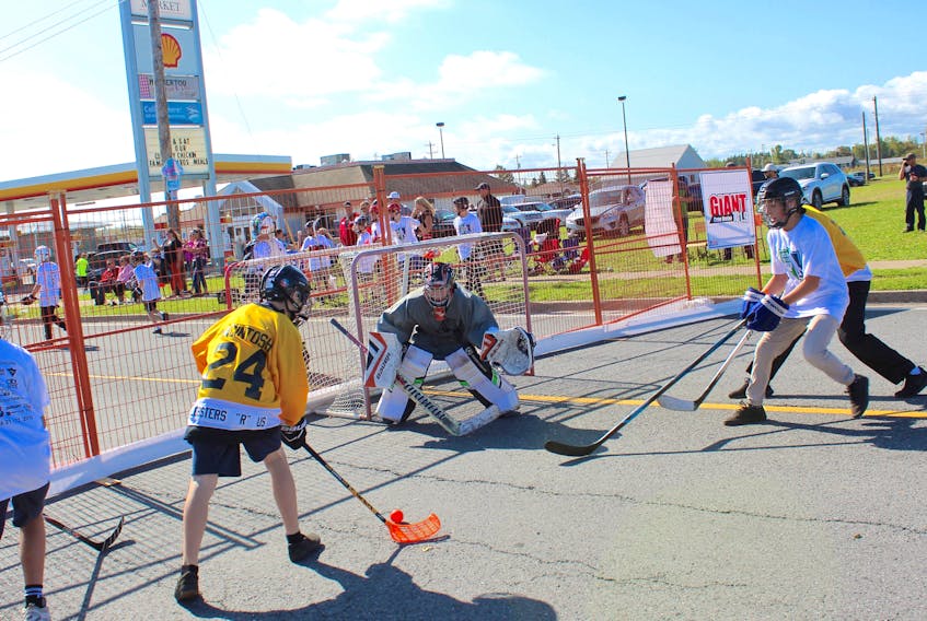 Cape Breton Bruins player Jake MacIntosh, left, tries to slip the ball past Backstreet Boys netminder Brody Campbell and teammate Curtis Fogarty during under-14 play of the sixth annual Because You Care Cup. Taking place Saturday and Sunday in Membertou, the event raised $62,929 to support the redevelopment of the Cape Breton Cancer Centre at the Cape Breton Regional Hospital in Sydney.