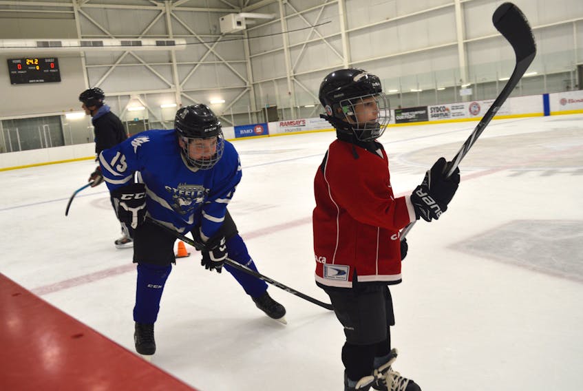 Ty Axworthy, left, closely watches the play of Gage Gibson, right, during Sunday’s hockey practice in Membertou. Gibson is a participant in a new program that teaches hockey skills to special needs children. Axworthy is a peewee player for the Sydney Steelers and one of the program’s volunteers.