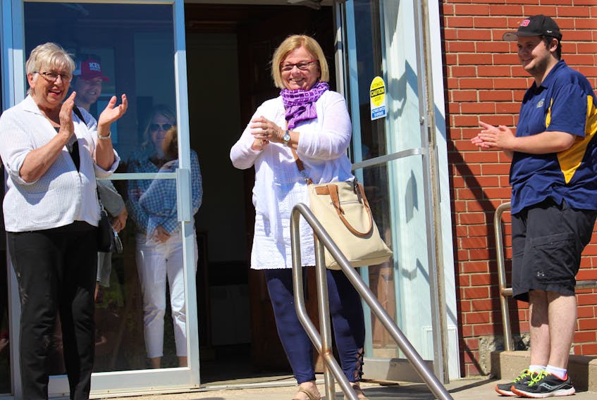 Supporters applaud Inverness County Warden Betty Ann MacQuarrie as she exits the municipal building in Port Hood Friday. A special meeting was called to debate her future as warden, however no action was taken against her leadership, pending planned review in November.