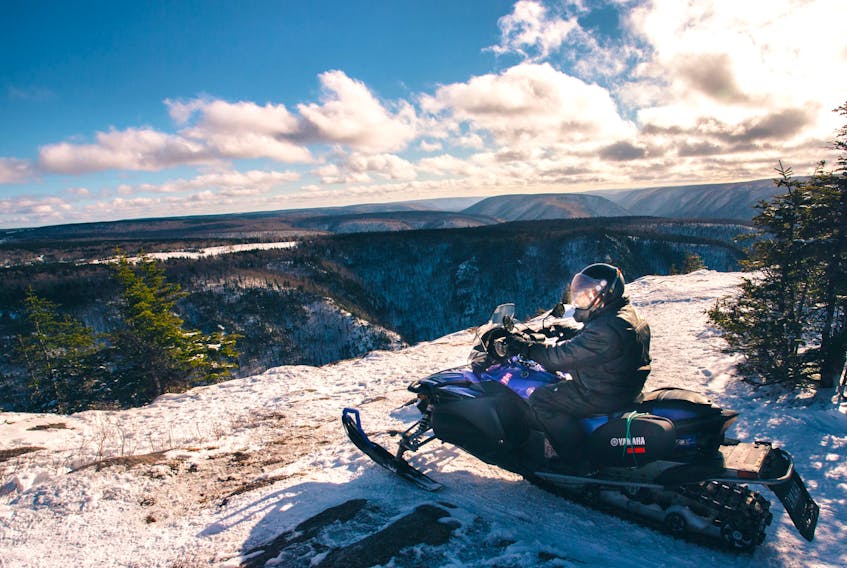 A snowmobiler looks out onto a bird's eye view of Cape Clear in the Cape Breton Highlands.