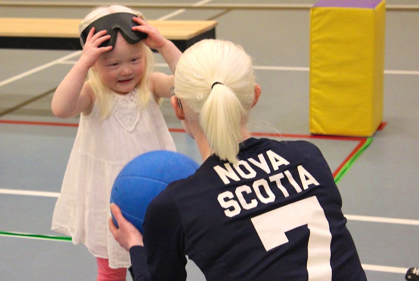 Three-year-old Lily Carmichael takes off her blindfold goggles as she speaks to women’s senior provincial goalball player Jennie Bovard of Halifax.