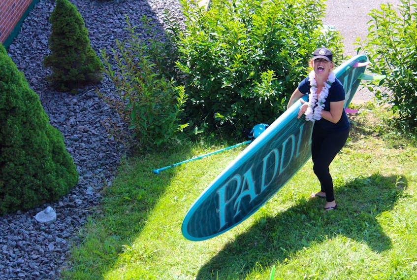 Michelle Richards, a certified Paddle Canada instructor, grabs a stand-up paddle board for a participant during the learn to paddle event at Just Paddle It in Eskasoni on Sunday.