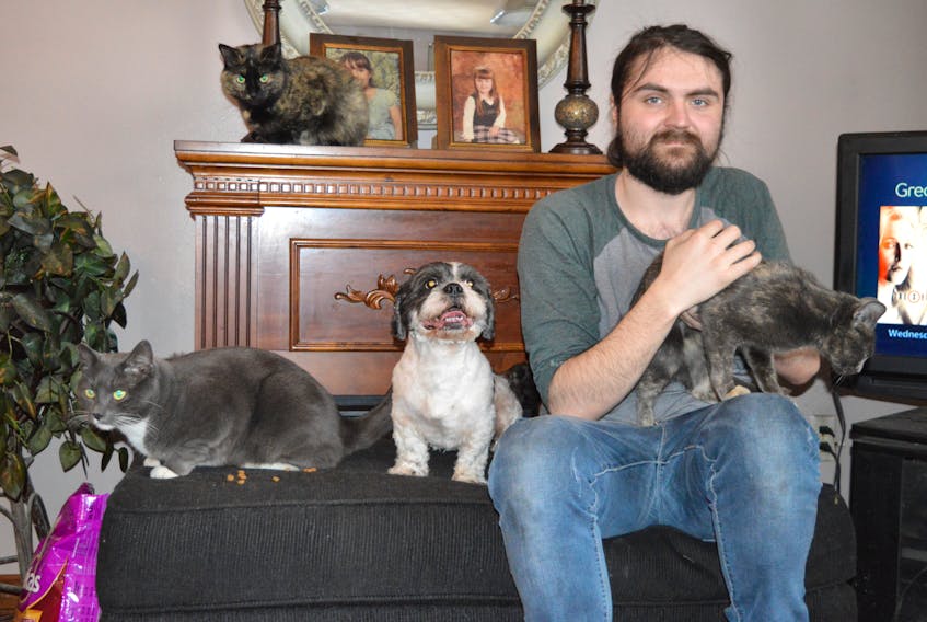 Alex MacLean, 25, of 47 Maple Street, Scotchtown, cuddles with family pets rescued in a house fire his family endured on Jan. 18 including, from left, cat Apollo, Shih Tzu dog JoJo, and cats Little Girl and, up in back, Sugar. Alex’s mother, Cathy MacLean, admits she stayed in the house longer than she should have after her children were safe because she was frantic to try and save their pets. The family was eventually able to rescue their dog and three cats. One cat is still missing and a turtle, a gecko lizard and a fish died in the fire.