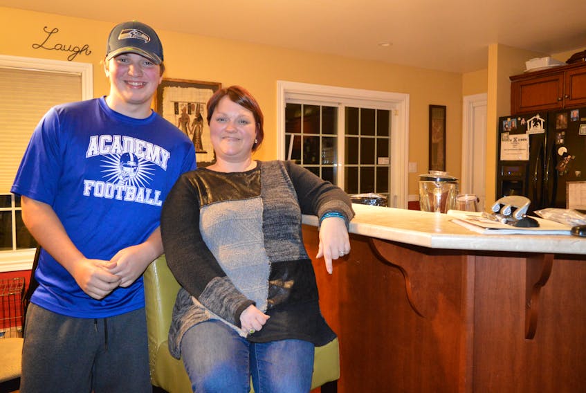 Riley Mackie, 15, stands beside his mom, Suzie, in the kitchen of their Gardiner Mines home. Before playing football, Riley was withdrawn and shy, a constant target of bullying. Now he is confident, happy and hopes his story will help others who are victims of aggression see there is a light at the end of the tunnel. Nikki Sullivan/Cape Breton Post
