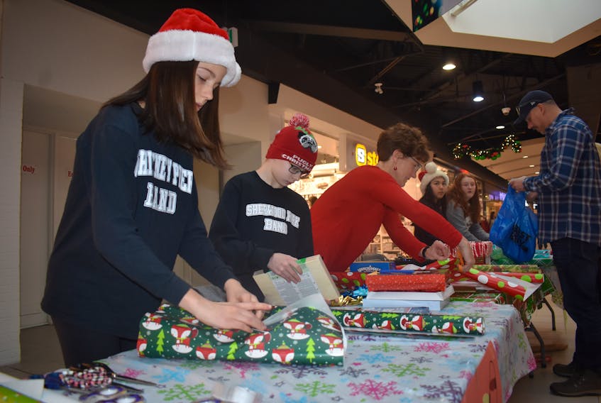 Last-minute shoppers were pleased to come across a gift-wrapping service at the Mayflower Mall on Monday. From the left are Sady Parnaby, Connor Gray and Jill Perry. They were wrapping gifts as part of fundraising efforts for the Whitney Pier Memorial Junior High Grade 8 school band trip to Alberta.