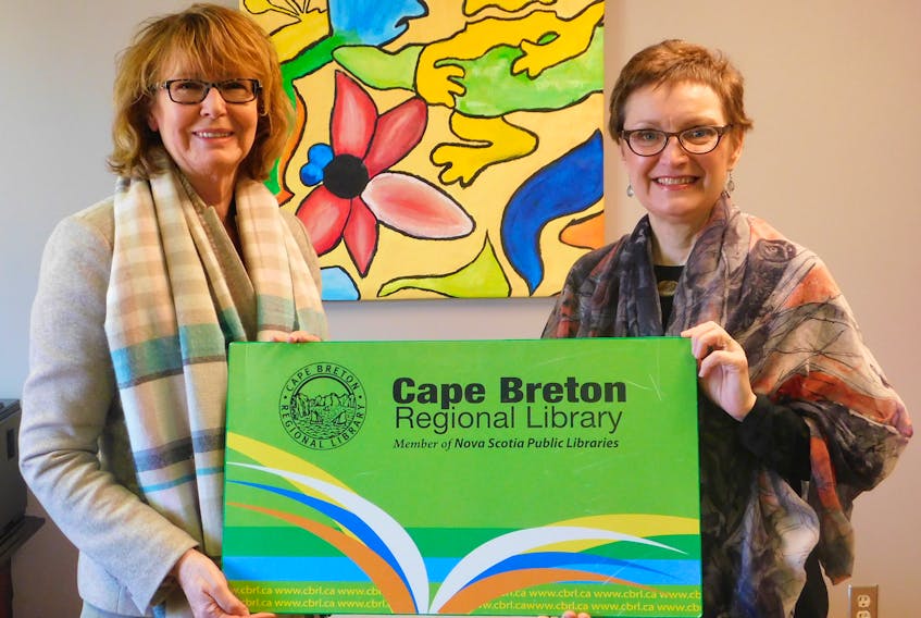 Beth MacIsaac, left, superintendent of the Cape Breton Victoria Regional Centre for Education, and Faye MacDougall, regional librarian for the Cape Breton Regional Library, show an image of the public library card that will be made available to every Grade 4 student.