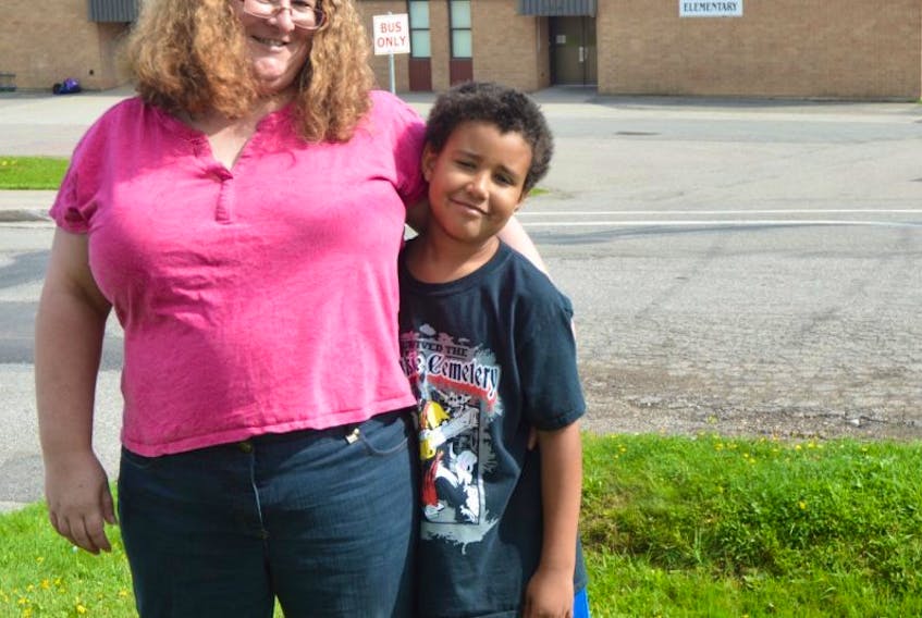Susan Kayombo stands beside her eight-year old son Keenan in front of his school. She said Keenan is a victim of bullying and racial slurs.
