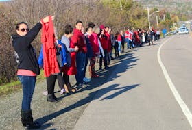 A woman holds up a red dress as the last group of people who participated lined the highway in We'koma'q First Nation on Thursday for a vigil held in memory of Cassidy Bernard and all missing and murdered Indigenous people. More than 100 people from around Cape Breton attended the vigil which lasted 4,365 seconds (4,000 seconds representing the number of missing and murdered Indigenous women and girls and 365 seconds for each day Cassidy hasn't been with her family.)
