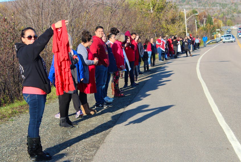 A woman holds up a red dress as the last group of people who participated lined the highway in We'koma'q First Nation on Thursday for a vigil held in memory of Cassidy Bernard and all missing and murdered Indigenous people. More than 100 people from around Cape Breton attended the vigil which lasted 4,365 seconds (4,000 seconds representing the number of missing and murdered Indigenous women and girls and 365 seconds for each day Cassidy hasn't been with her family.)