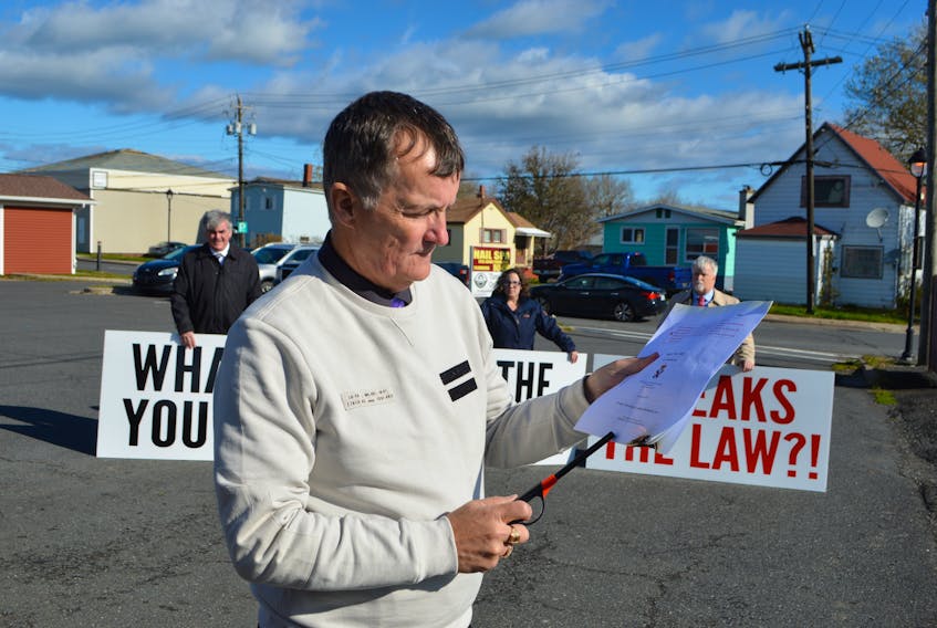 Sydney Crown prosecutor Steve Drake burns a copy of Bill 203, while other local Crown prosecutors, back left, Gerald MacDonald, Glenn Gouthro and Darcy MacPherson, hold up signs protesting the bill, behind Glace Bay MLA Geoff MacLellan’s office Thursday in Glace Bay. The prosecutors walked off the job Wednesday in protest of the bill which they say takes away their right to binding arbitration to settle contract impasses.