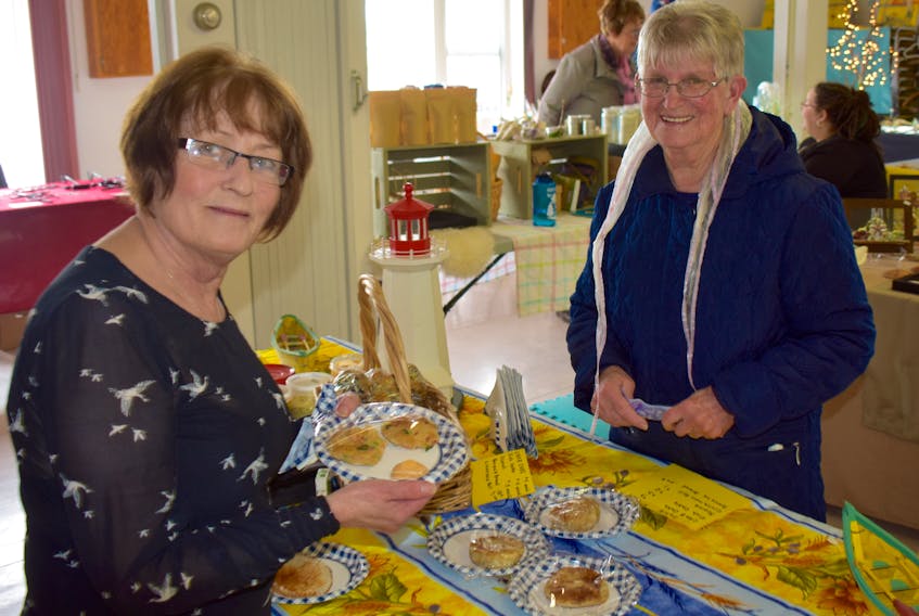 Louise Carter, left, sells the last of her crab cakes to Chris Gartland at the Louisbourg Market on Thursday. Carter was one of about two-dozen vendors set up in the Louisbourg Seniors Social Club in expectation of the season’s first cruise ship. However, the MS Fram opted not to enter the harbour due to rough seas.