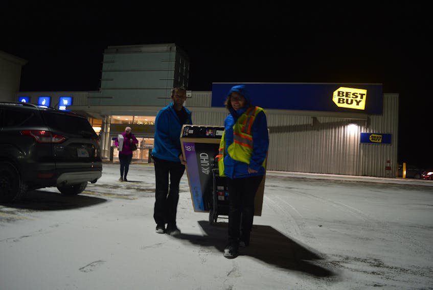 Big televisions were popular items at the Boxing Day sale at Best Buy on Wednesday. Store employees Jason Turnbull and Cynthia MacNeil, are shown carrying one to a customer’s car. GREG MCNEIL/CAPE BRETON POST