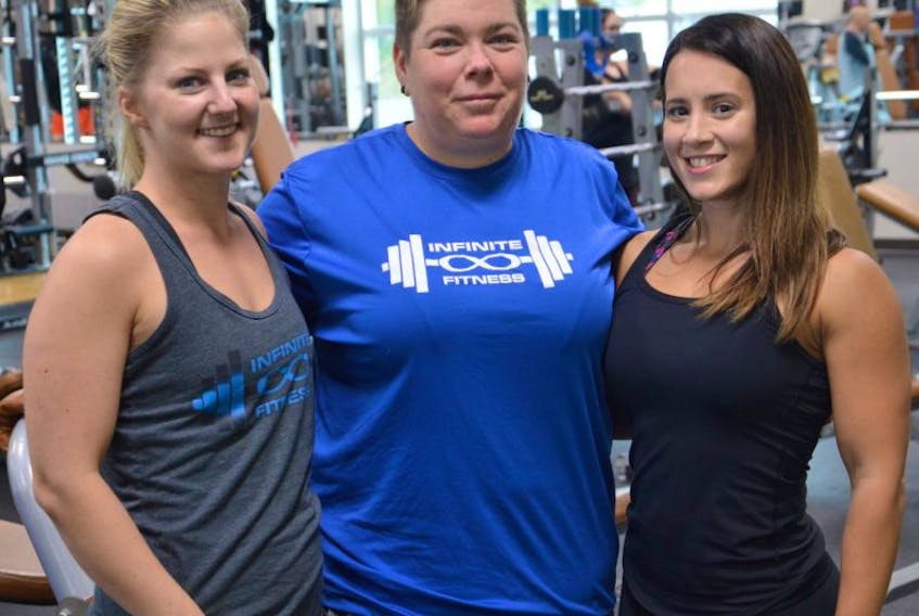 Owners of Infinite Fitness, Ashley Petrie, left, and Laura Boudreau, right, stand with Julie Forrest at Ascendo Fitness on Wednesday. Forrest is a client who has been taking part in the company’s Every Body Transition Challenge since May.
