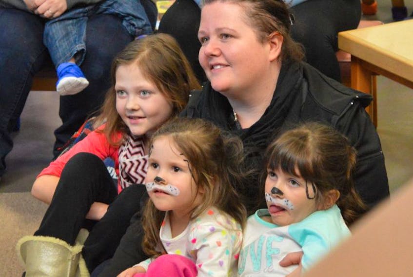 Sabrina Vatcher and daughters, from left, Ashley, Sofia and Emma, are studies in concentration as they take in the puppet show during Family Literacy Day celebrations at the James McConnell Memorial Library in Sydney on Sunday.