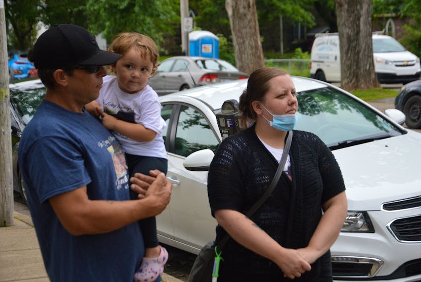 Nathan Joneil Hanna’s stepfather, Steven Penney, left, Joneil’s two-year-old daughter, Harper, and his mother, Jen, wait to speak with reporters Wednesday outside the Sydney Justice Centre. The family offered their reaction to the withdrawal of an obstruction charge filed against a Bras d’Or man in connection with Joneil’s death in 2018.