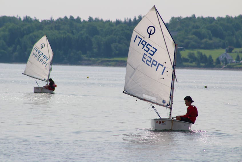 Alexandra Young, left, and Josh Gogan are shown off in the distance in the waters off of Seaview Drive in North Sydney on Tuesday. The learn-to-sail and junior sailing programs are in full swing at the Northern Yacht Club this summer and both are program participants.