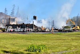 Firefighters wet down hot spots on the afternoon of July 7 following a massive blaze that destroyed the historic lodge at the Inverary Resort in Baddeck.