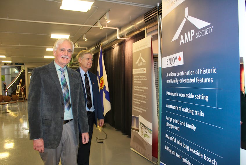 Cyril Aker and Brian Ferguson from the Atlantic Memorial Park Society pose beside slides at the Joan Harriss Cruise Pavilion on Friday. The slides outline details of the planned war memorial at Chapel Point in Sydney Mines that was the recipient of federal and provincial funding on Friday.