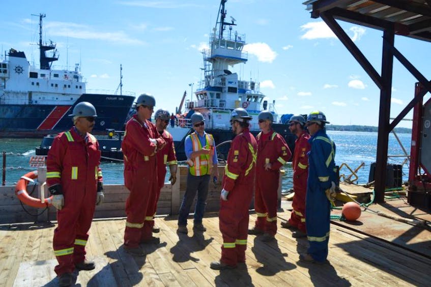 Mike Moore, centre in yellow vest, is the region manager for commercial interests for Heddle Marine. He’s shown giving instruction to some of the company’s workforce prior to the start of demobilizing a barge at Sydport.