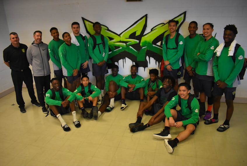 St. Patrick’s High School basketball team (The Irish) pose for a picture near the “BEC” graffiti tag inside the Breton Education Centre cafeteria on Feb. 6. The team from Ottawa, Ont. came down to compete in the Coal Bowl Classic 2019 and had hosted the BEC boys basketball team for a tournament in Ottawa in the fall. The players have a close connection that can be seen on and off the court and it might be due to how multi-cultural the team is. Picture here are: (front row from left) Ricardo Sylvestre, Ben Garcia, Josh Rutarindwa , Armand Malumalu, Patrick Johnson, Frantzini Cambronne, Andrew Bui (back row from left) Ed MacPherson (coach), Matt Koeslag (coach),  Precieux King, Ngatangwe Katijaani, Matthew Kendall, Chrys Kazadi, Albert Openia, James Merina, Adam Eslava, Sam Saint-Val.