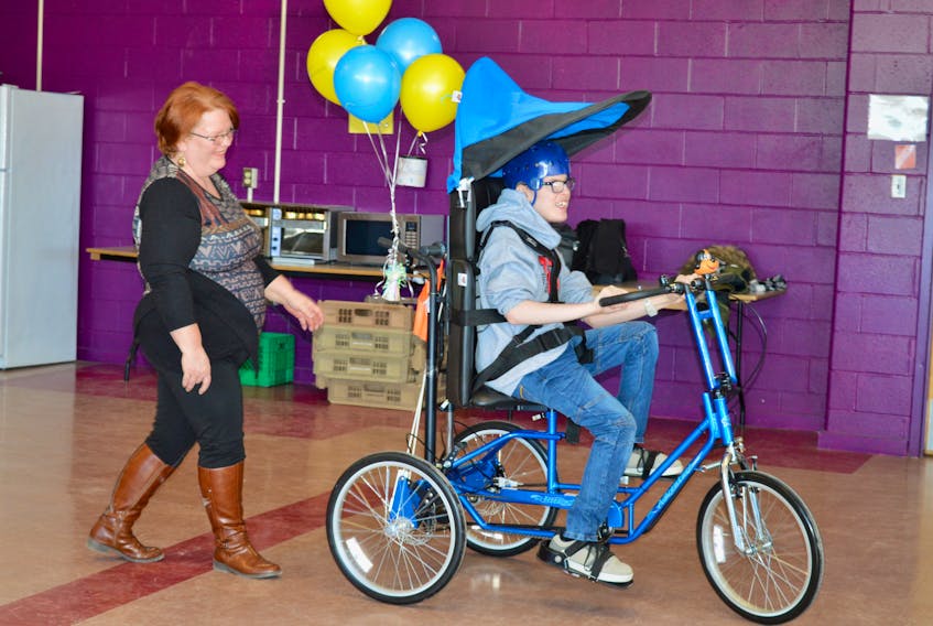 Kevin Carey takes a spin around the cafeteria at Glace Bay High under the watchful eye of his mother, Debbie Hastie, on Friday morning after Carey received the scooter from the Children’s Wish Foundation. See page A2 for the full story.