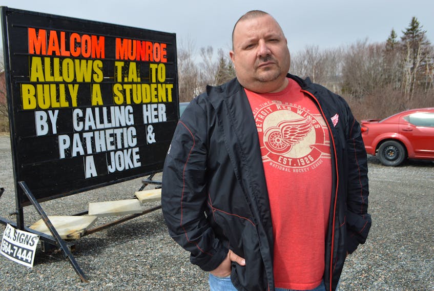 Paul MacDonald, a Membertou band councillor and owner of Belly Busters Pizza and Donair in Membertou, stands near a billboard in front of his business. He says he put up because his daughter, a student at Malcom Munroe Memorial Middle School in Sydney River, was verbally abused and the Cape Breton-Victoria Regional Centre for Education refuses to help.