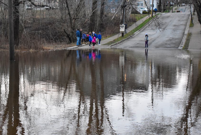 A group of local residents checks out the flooding on St. Peters Road in Sydney on Sunday. The waters of the Wash Brook reached its highest levels since the devastating flooding on the Thanksgiving weekend in 2016. Much of the same area was affected with some of the now-houseless properties once again submerged by the flood waters.