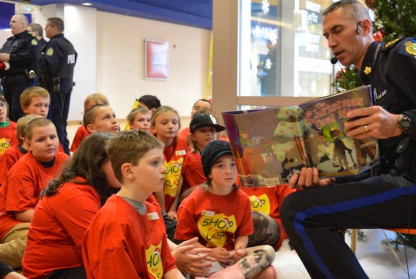 Inspector Robert Walsh reads a book to students participating in the Shop of the Class event at Mayflower Mall on Thursday. A total of 48 students from the Cape Breton-Victoria Regional School Board took part in the annual event.