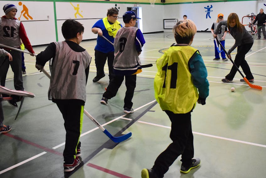 Sherry Harris, left, plays floor hockey with children as part of the Cape Breton Regional Police Boys and Girls Club, which takes place every Saturday at the John Bernard Croak VC Memorial School gym in Glace Bay. Harris was a cadet with the regional police last summer.