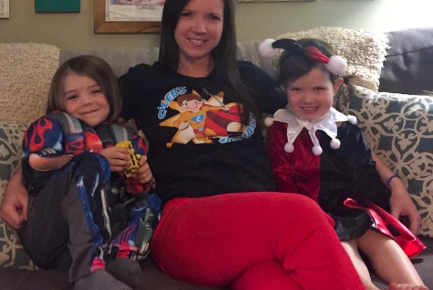 Nicole Forgeron, middle, sits beside her four-year-old twins, Lauchlin, left, and Emery MacArthur. The twins are wearing their costumes for the Superhero Walk, Run or Fly event in memory of their brother Caleb who died of cancer.