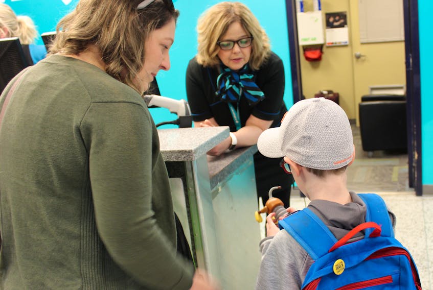 Crystal Lahey and her son Garrett, 7, received help checking their bags from WestJet customer service agent Rosemary Murrin during an Autism Aviators session Saturday at the J.A. Douglas McCurdy Airport in Sydney.