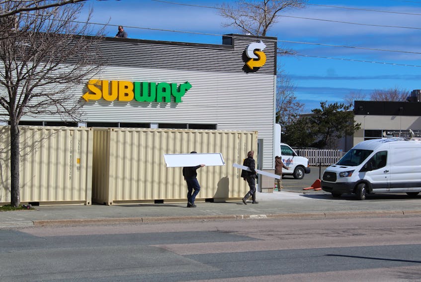 Two men carry building materials into the New Waterford Subway on Plummer Avenue on Thursday. Anticipated opening for the new franchise location was expected to be December but delays have caused the opening to be pushed to June 1 “at the latest” according to owner Emily Pelley.