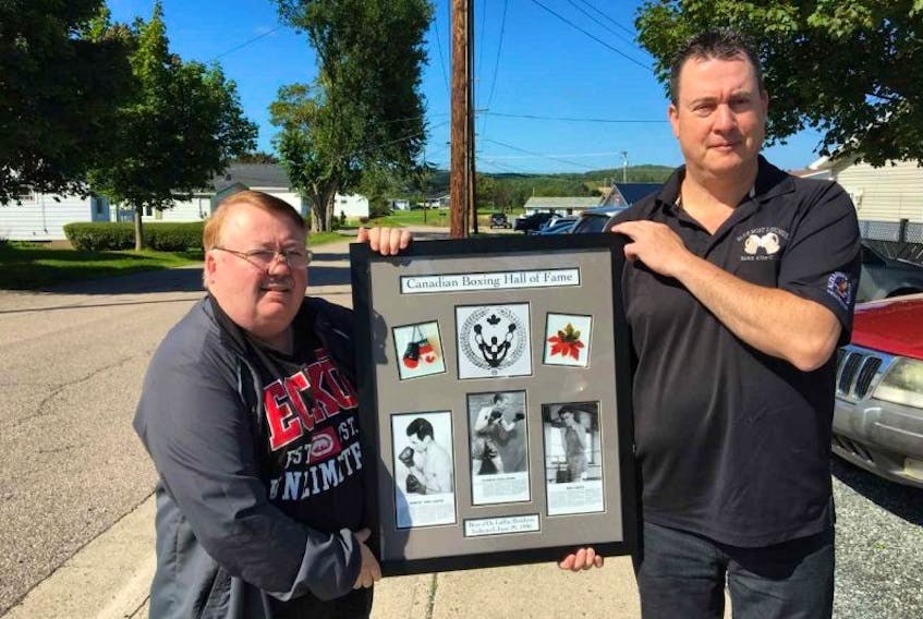 Ron Laffin, left, and Paul Day, owner of the Blue Mist Tavern, hold a special picture tribute in front of the local tavern on Wednesday. The tribute is in honour of Nicholas (Nick) Laffin, Bill Laffin and Robert (Bob) Laffin, who were each inducted into the Canadian Boxing Hall of Fame in 1996.