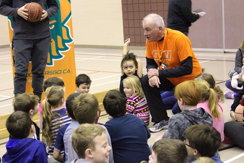 Retired teacher Gary MacLean speaks to students gathered at the Boularderie Elementary gymnasium about exercise, healthy eating, limiting sugar, along with drinking plenty of water and getting enough rest as part of the CBU Athletics student visit program.