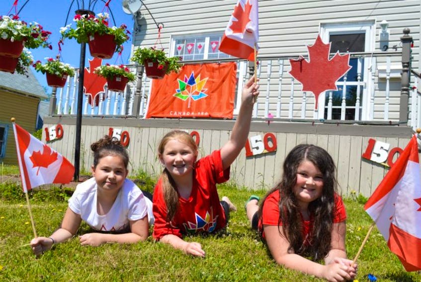 Cousins, from the left, Taylor Ogley, 10, of Glace Bay, Jayln Murphy, 9, of Alberta and Madelynn Matheson, 10, of Glace Bay, relax in the yard of grandparents Darlene and John Matheson in Glace Bay which they helped decorate for Canada 150. They're ready for Canada Day and there's lots to do, no matter where you live.