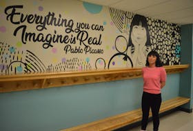 Stephanie Steele stands near one of the murals she painted on the walls of Riverside Elementary School, which she completed in August.