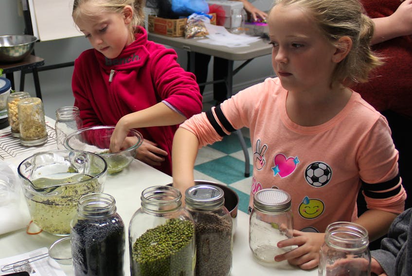 Nine-year-old Abigail Hatcher, left, and her twin sister Brianna Hatcher wash beans for sprouting as part of a self-esteem workshop at the New Waterford Library on Oct. 3. The four-week workshop was organized by library clerk Janet Rizzo.
